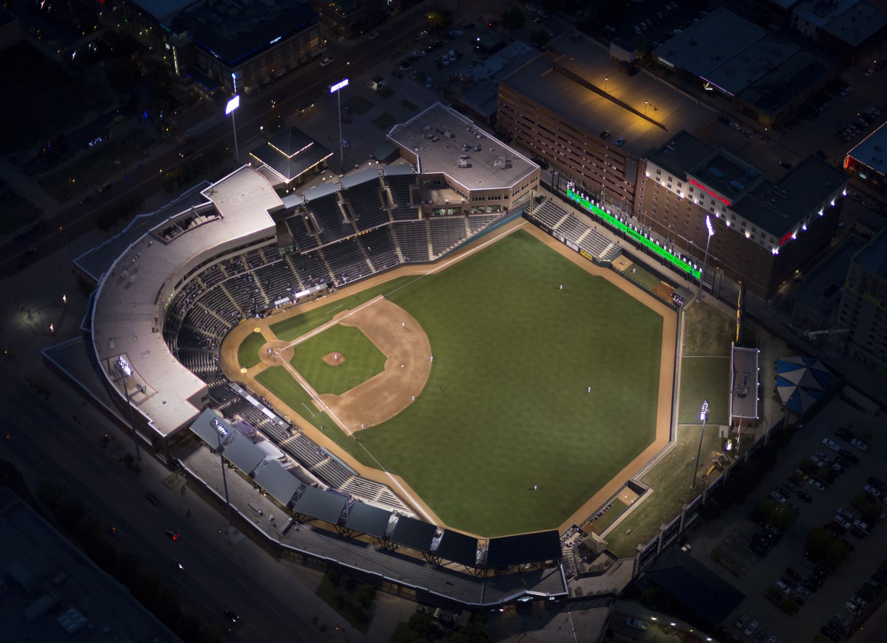 Chickasaw Bricktown Ballpark under lights at night, aerial view
