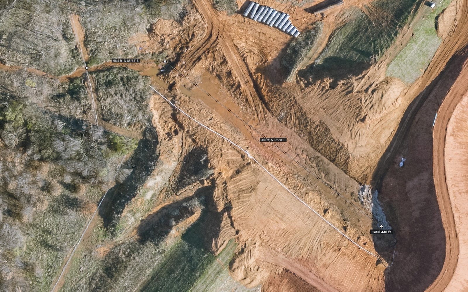 Plan view of a lake dam under reconstruction in March 2021, straight down and north up, with a two-segment measured line along the embankment: 98.5 feet, then 341 feet, 440 feet in all